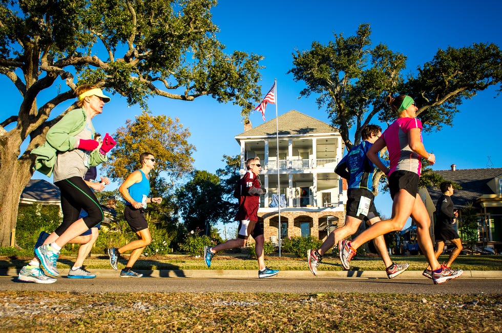 group of runners participating in a race with a historical building in the background mississippi gulf coast marathon