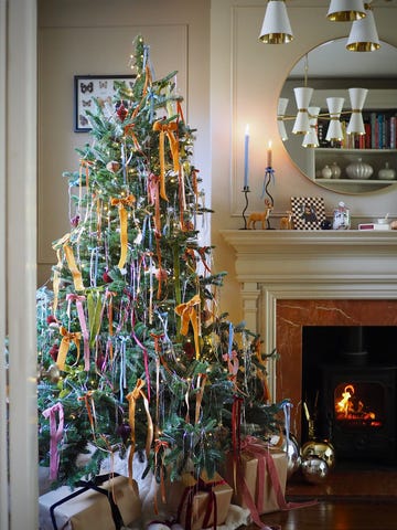 christmas decorating design trends, decorated christmas tree with ribbons and ornaments in a cozy living room