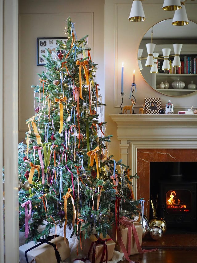 christmas decorating design trends, decorated christmas tree with ribbons and ornaments in a cozy living room