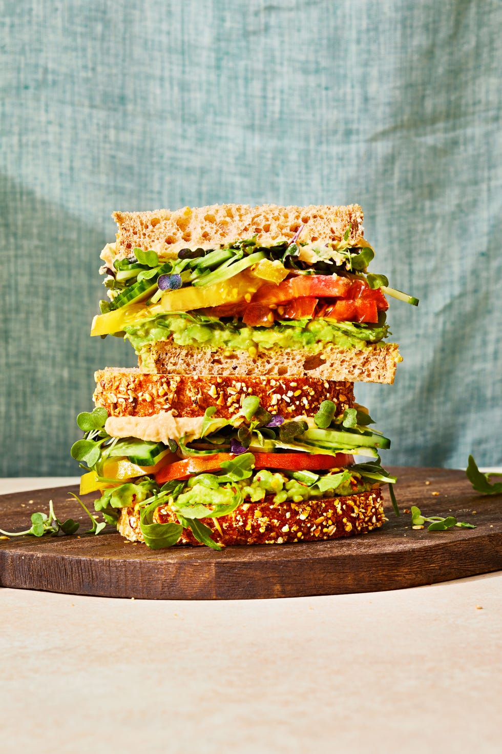 a stacked veggie sandwich with tomato, avocado, cucumber and arugula