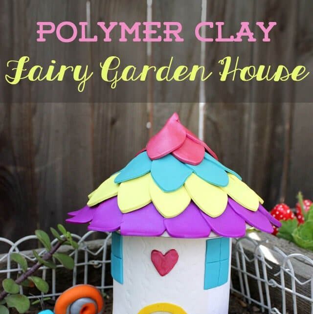 a clay fairy house sits in the corner of the garden