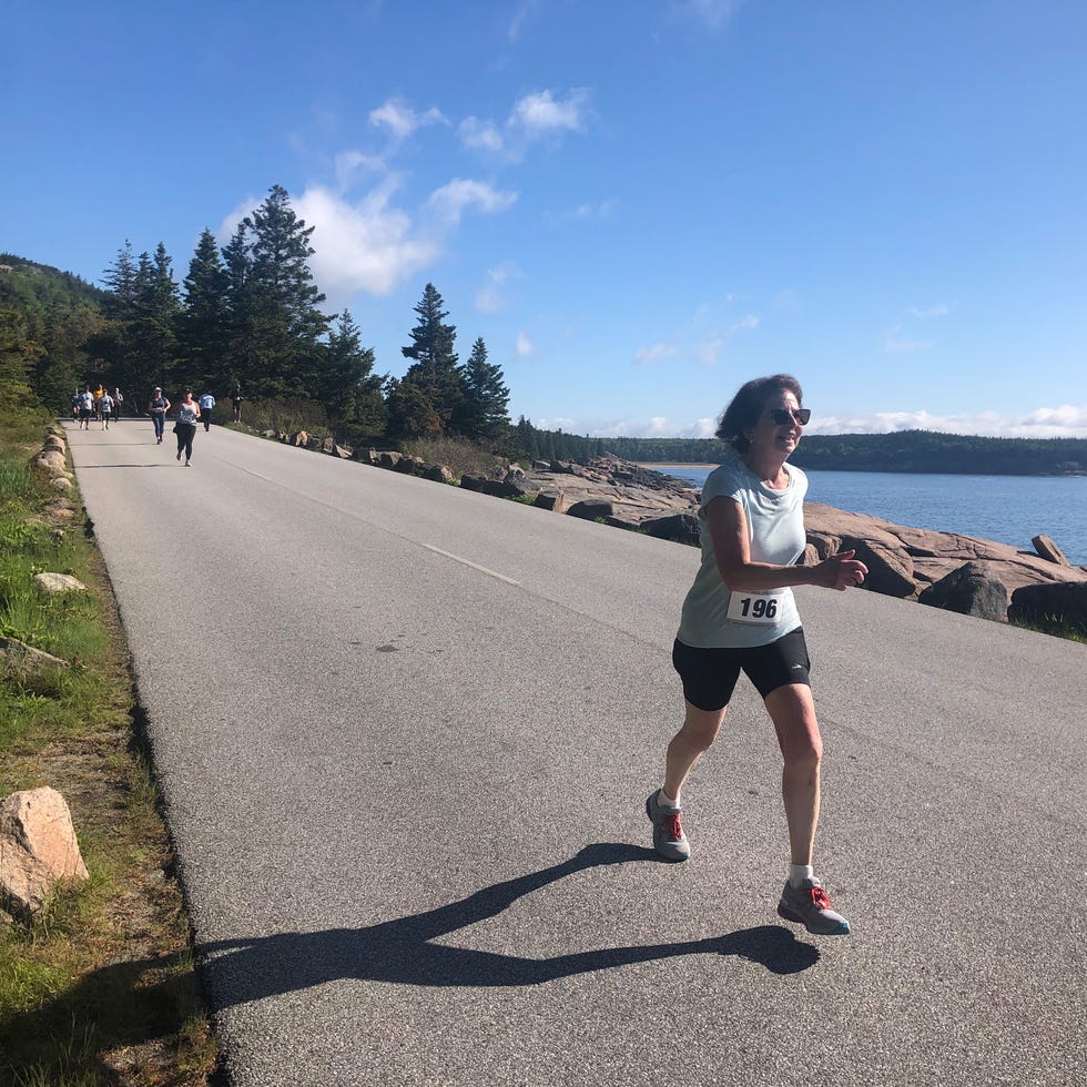 a runner in the acadia half marathon runs along a rocky beach