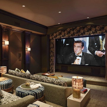 home theater with big movie screen, sconces on walls, mini table lamps, and couches