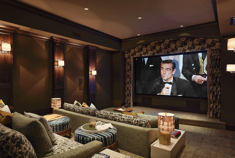 home theater with big movie screen, sconces on walls, mini table lamps, and couches