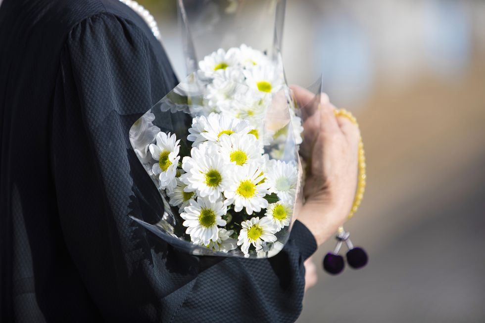 a funeral and visit to a grave of japan the woman of the senior worships the ancestral soul in a black mourning dress i hold white chrysanthemum bunch and beads in a hand