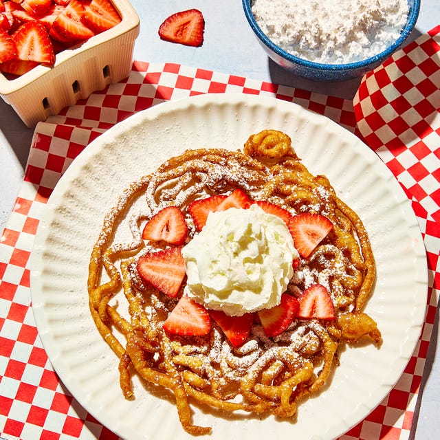 funnel cake topped with strawberries and powdered sugar