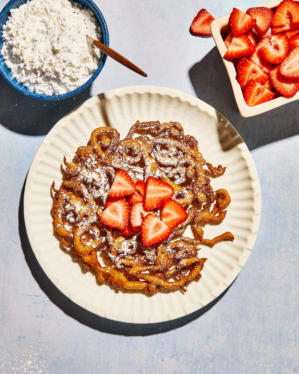 funnel cake topped with strawberries and powdered sugar