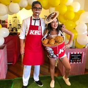 bucket of fried chicken costume with colonel sanders in white plus red kfc apron, black western tie, white mustache, goatee