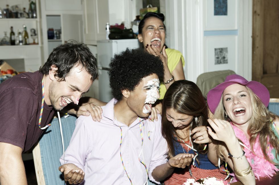 man with icing on his face laughing with friends