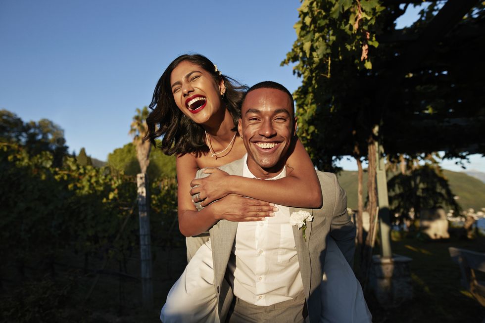 laughing man piggybacking woman in vineyard