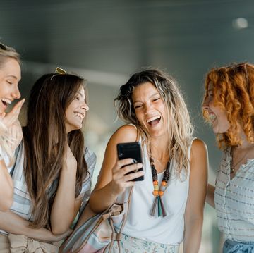 four laughing female friends looking at a smartphone