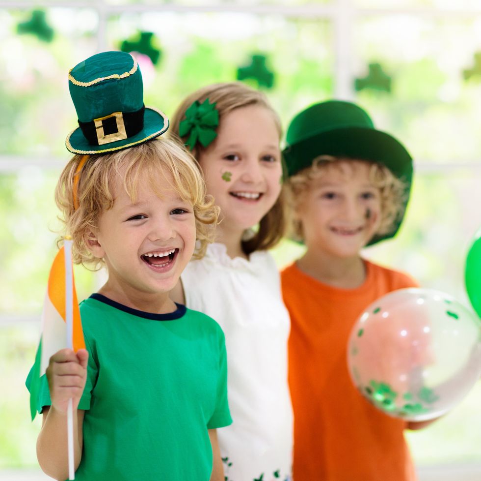 family celebrating st patricks day irish holiday, culture and tradition kids wear green leprechaun hat and beard with ireland flag and clover leaf children having fun at st patrick party