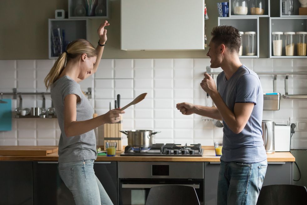 funny young couple dancing together enjoying cooking in the kitchen