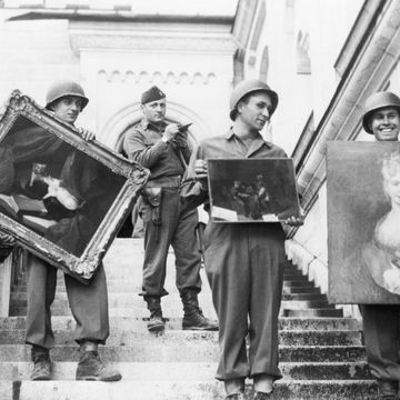 leden van de monuments men staan op de trappen van slot neuschwanstein met gestolen kunst.