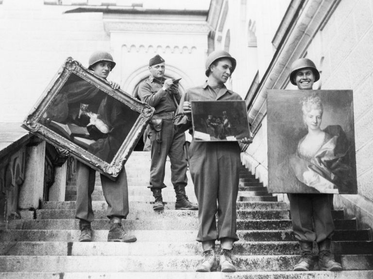 leden van de monuments men staan op de trappen van slot neuschwanstein met gestolen kunst.