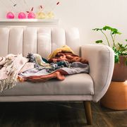 light pink futon in living room with throw blankets and potted plant