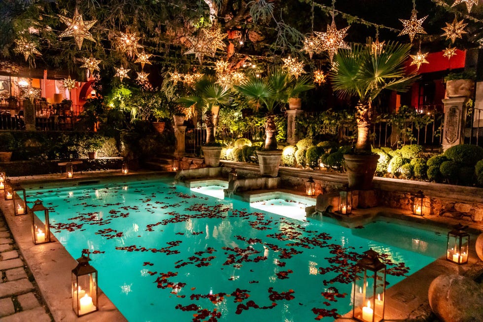 decorative outdoor space featuring a welllit pool rose petals and starshaped lanterns