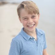 prince george smiles while posing on a beach