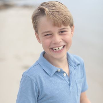 prince george smiles while posing on a beach
