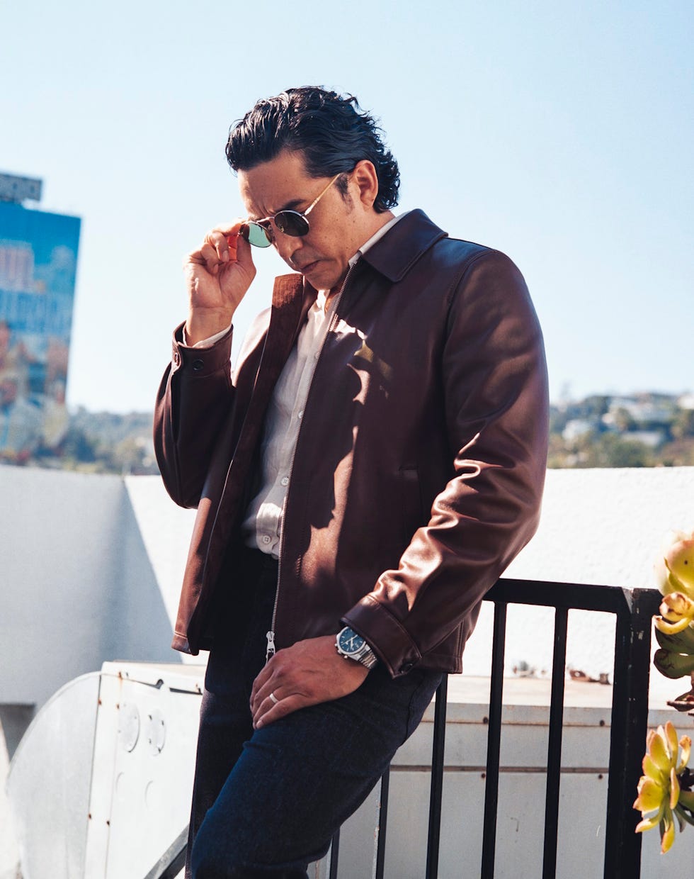 gabriel luna in a brown leather jacket and denim jeans in an outdoor urban setting