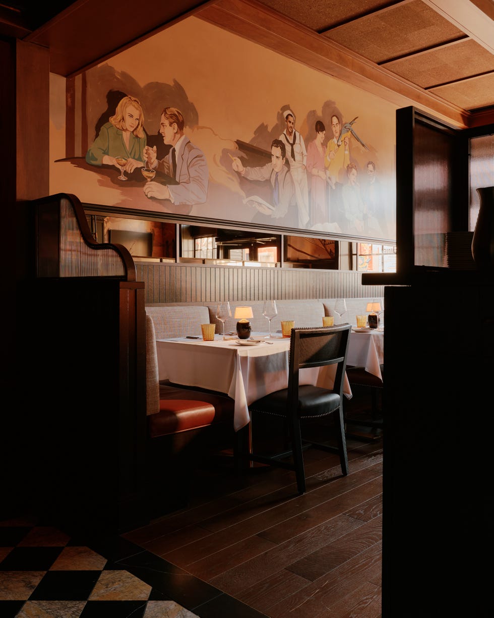 a colorful mural featuring different san francisco characters is painted on the wall surrounding dining table with white tablecloths