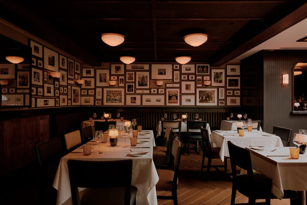 dining tables with white tablecloths and a wall of framed photos and memorabilia