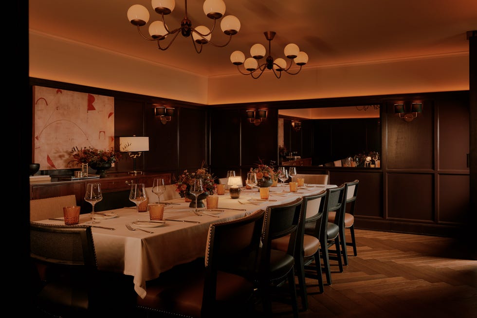 dining table with white tablecloth underneath two chandeliers