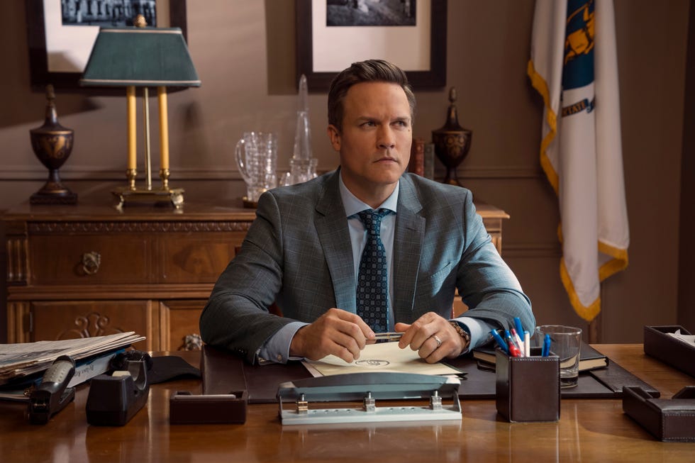 Scott Porter como Paul sentado en su escritorio en el episodio 302 de Ginny y Georgia.