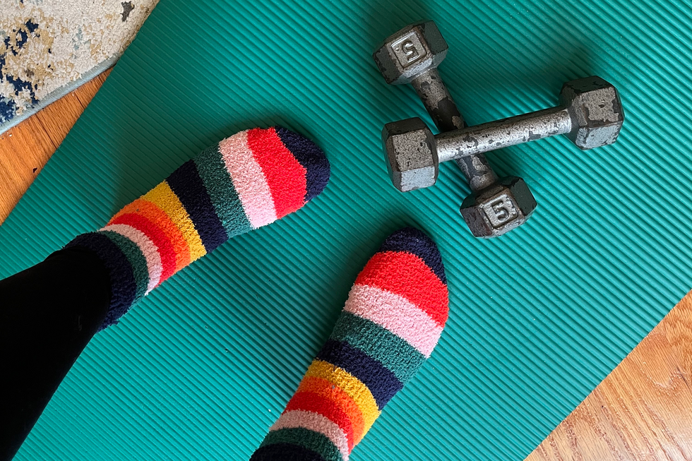 feet in striped socks and dumbbells on top of blue green thick yoga mat