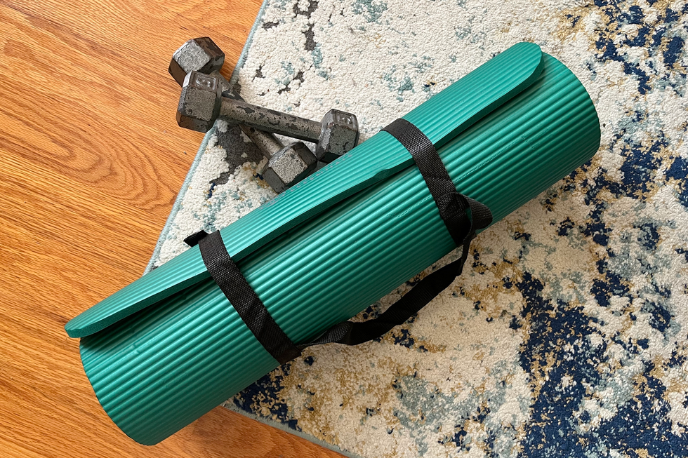 gaiam extra thick yoga mat rolled up on carpet next to dumbbells