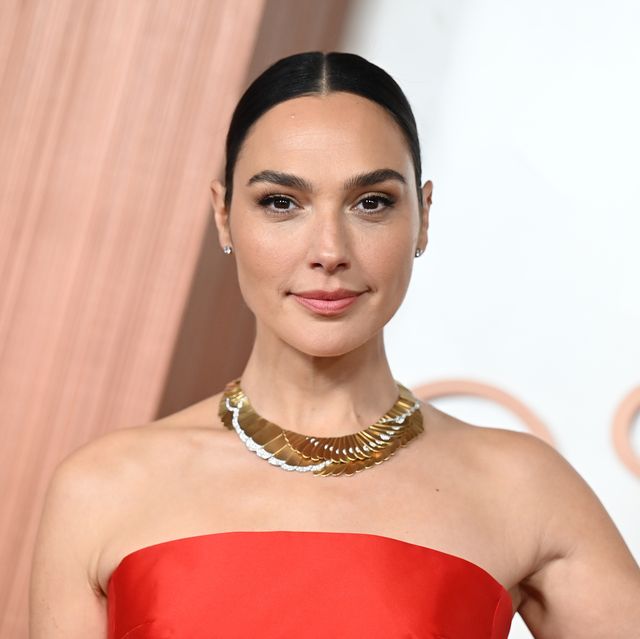 woman posing while wearing a gold necklace and red dress