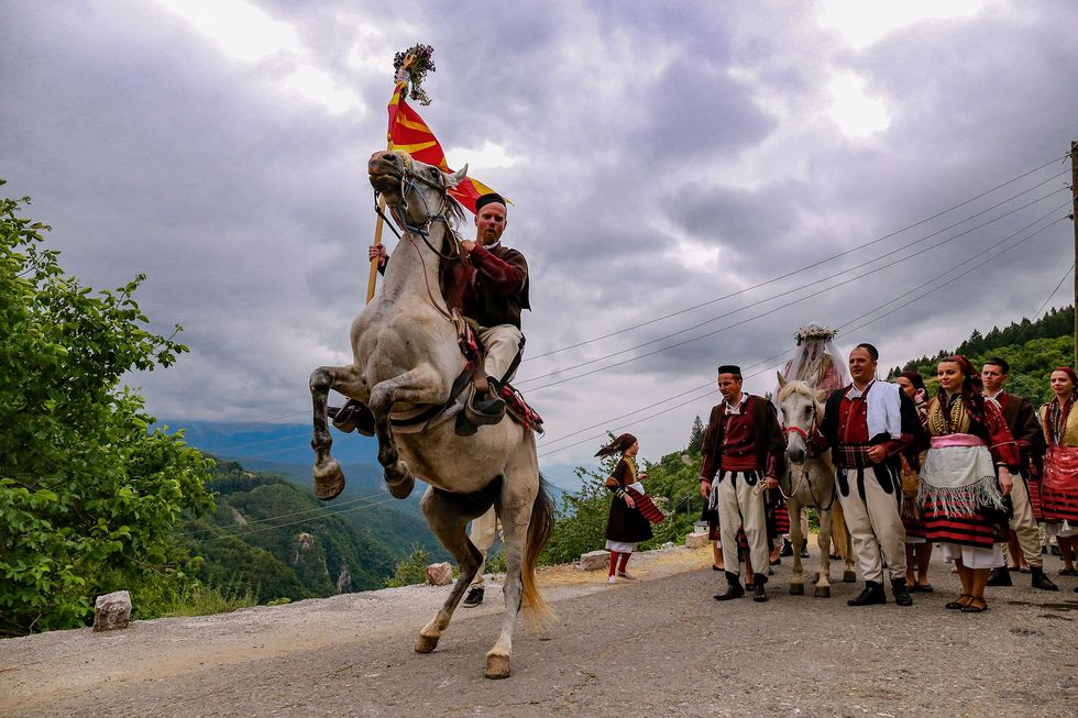De vlaggendrager of bajraktarot leidt de bruid en haar familie naar het huis van de bruidegom tijdens het jaarlijkse trouwfestival in Galinik in Macedoni