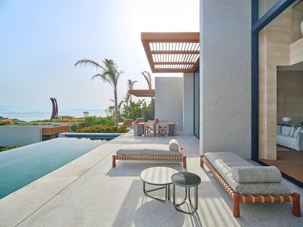 a pool and lounge chairs on a patio by a beach