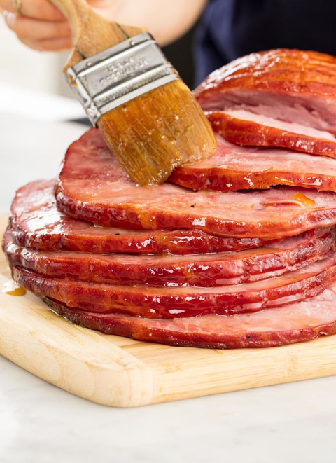 sliced baked ham with brown sugar glaze on wooden cutting board