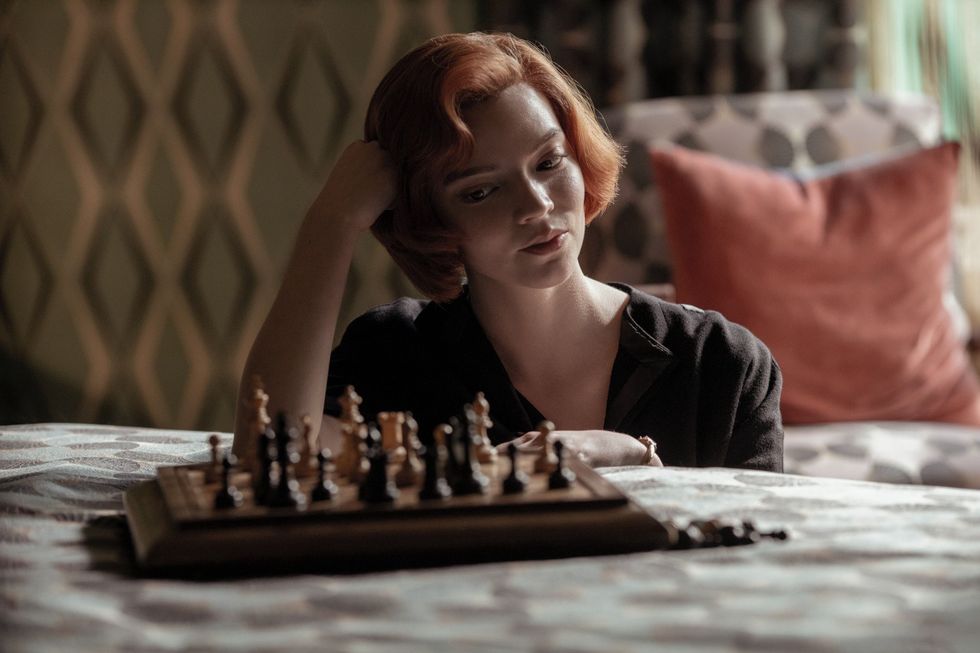 una chica mira el tablero de ajedrez