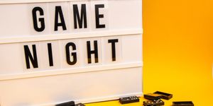 Game night text on lightbox with black dominoes on yellow background, table game