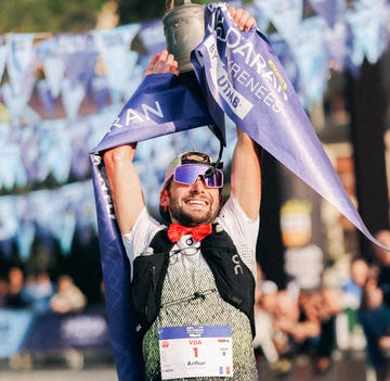 A triumphant athlete celebrating a victory while holding a trophy and banners