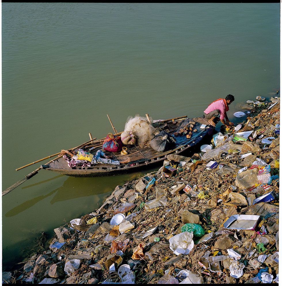 Visser Babu Sahni 30 en zijn zoon Himanshu Kumar Sahni 8 varen langs de oever van de Punpun een zijrivier van de Ganges Op het Indiase platteland wordt afval zelden ingezameld je vindt er veel lukraak gestort vuilnis zoals hier Het meeste plastic afval in zee wordt aangevoerd door rivieren