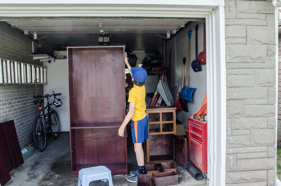 boy cleaning a bookshelf in the garage to use for organization and storage