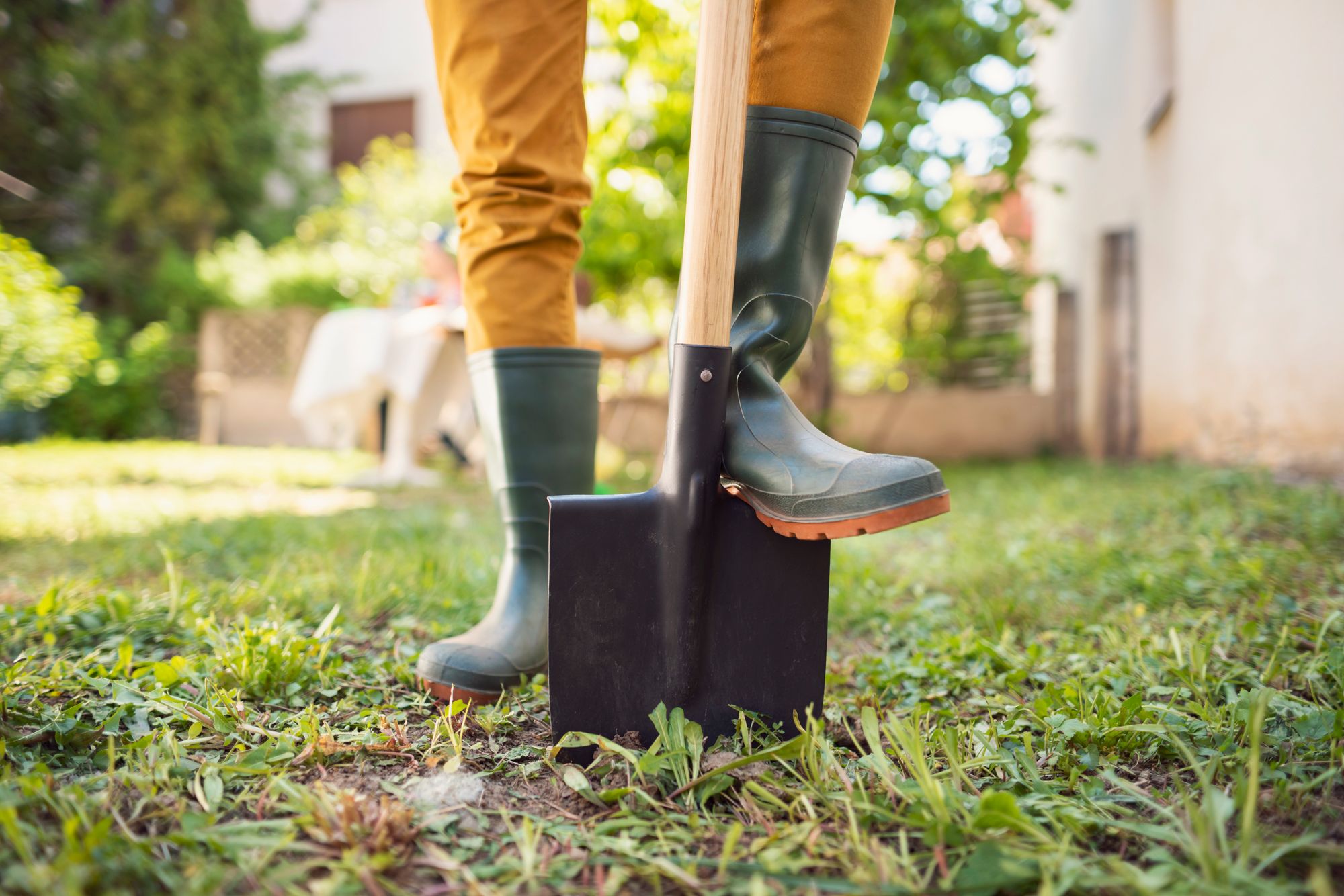 gardener standing on shovel in rubber boots