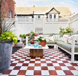 checkerboard flooring on garden terrace with green sofa and white trellis fencing