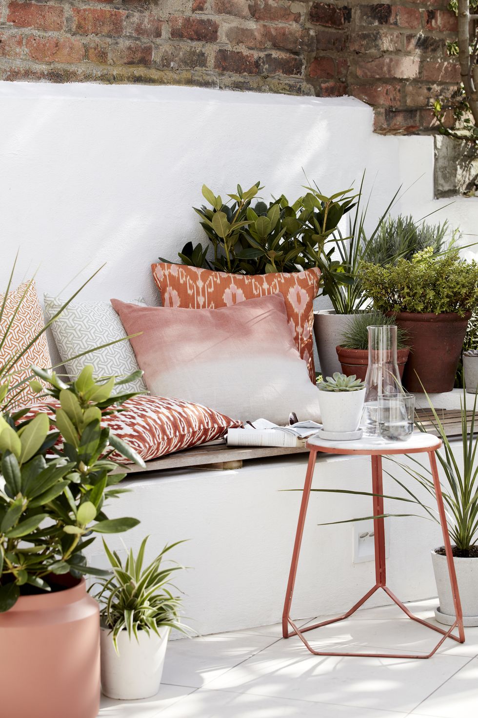 garden ideas, outdoor seating area filled with cushions, plants and a side table