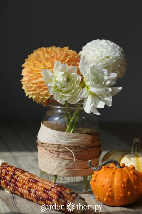 diy cornstalk decor like a jar with corn husks wrapped around it filled with fall flowers