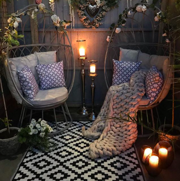 beautiful garden with hanging egg chairs, outdoor rug, cushions and candles