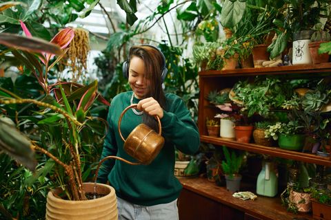 gardener in headphones watering plants