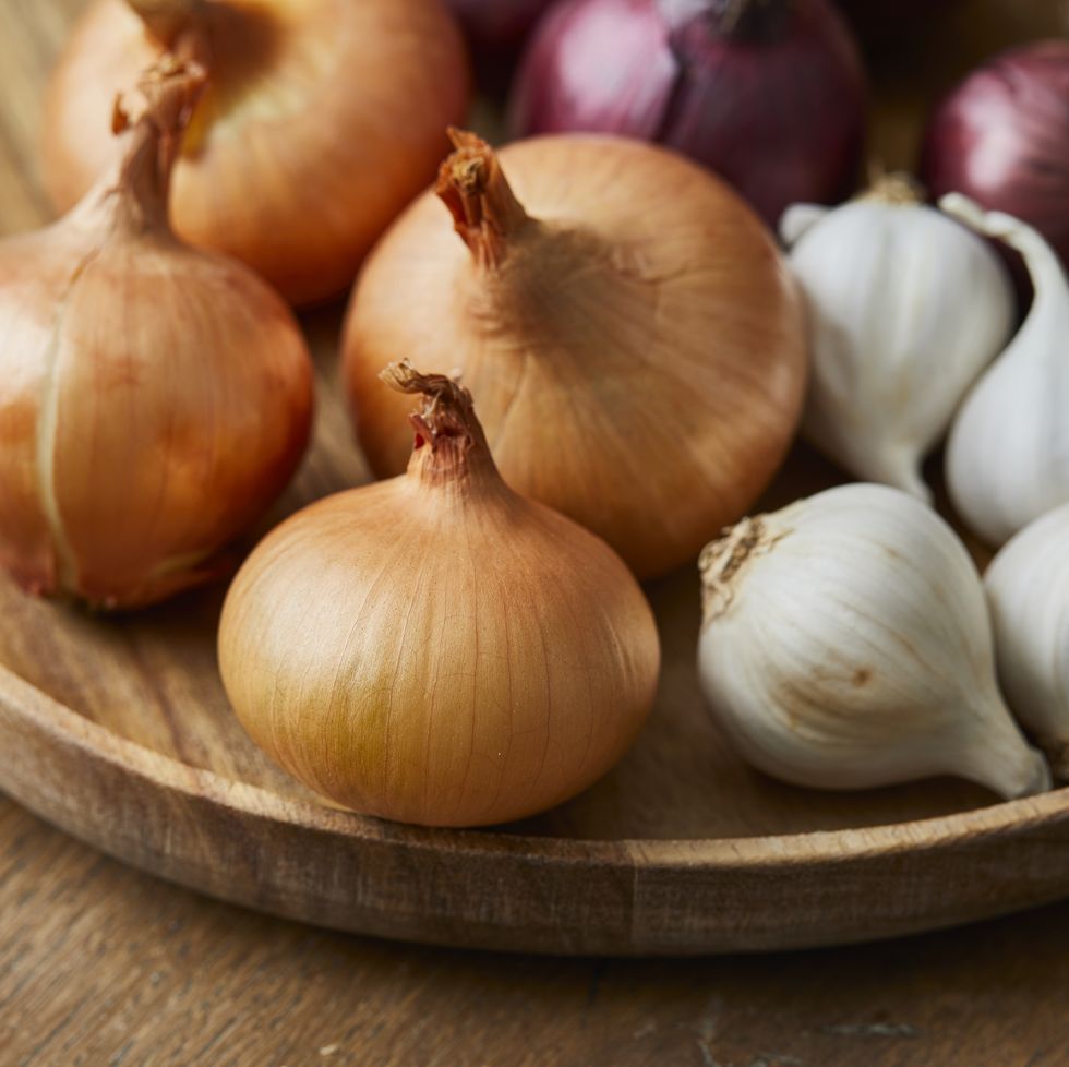 garlic, onion and spanish red onion on a wooden plate