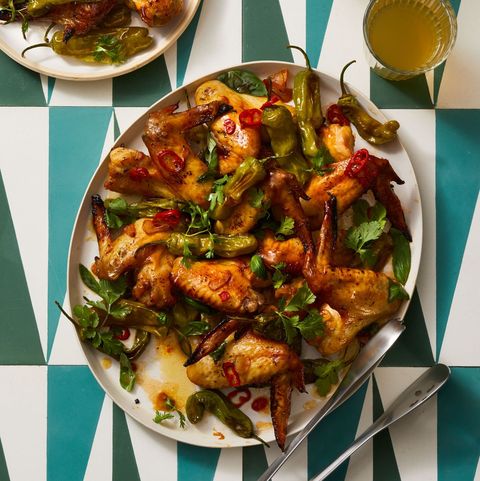 garlicky wings and shishito peppers on geometric tiled surface