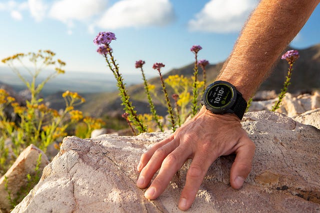la mano de un deportista apoyada en una roca y con el nuevo reloj deportivo garmin enduro