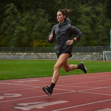 vrouw loopt over atletiekbaan in de regen