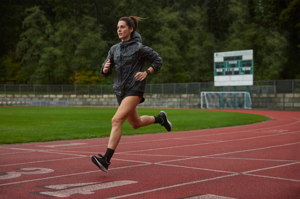 vrouw loopt over atletiekbaan in de regen